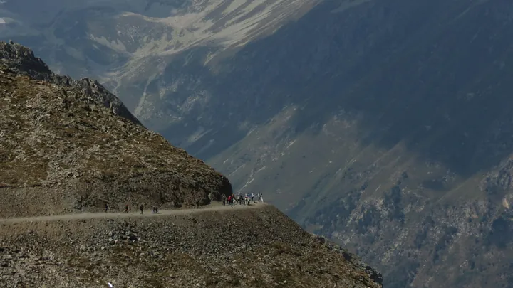 Cyclists on a mountain road with steep drop-off.