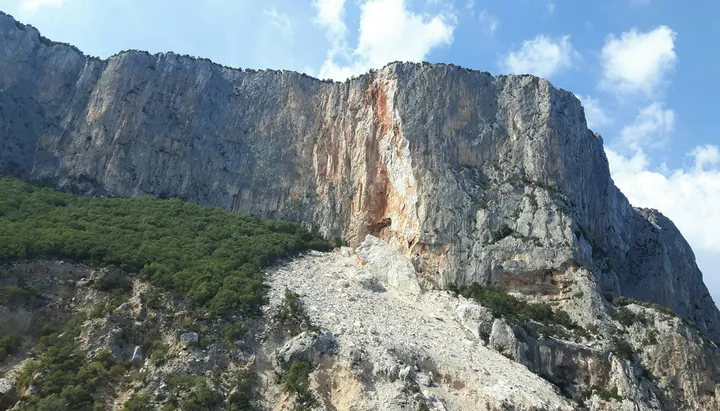 View of Sardinian world-famous sea cliffs, the Punta Plumare, from the sea. I took this whilst on a boat trip around the coast of Sardinia, which is a large Italian island, near Sicily, in the Mediterranean Sea. The sheer height of the rocks, and their colour fascinates me. It was such an enjoyable trip to caves and beautiful beaches; with azure sea I wish I could visit again.